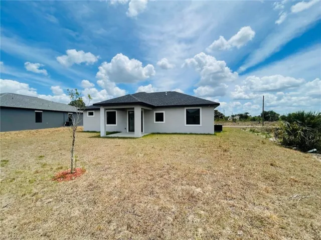 Rear view of property with a lawn, a patio area, and stucco siding