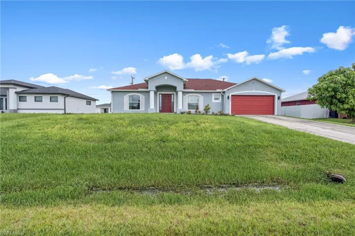 Ranch-style home with a garage and a front lawn