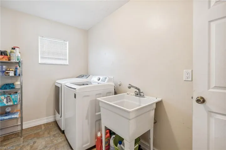 Washroom with washing machine and dryer, light tile patterned floors, and sink