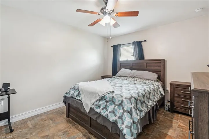 Tiled bedroom featuring ceiling fan
