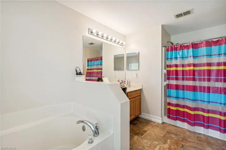 Bathroom featuring tile patterned floors, vanity, and a bath