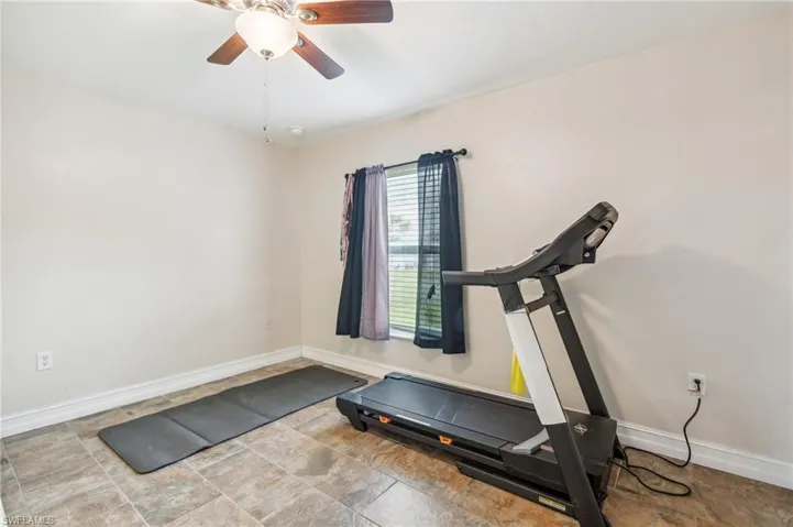 Exercise area with ceiling fan and light tile patterned floors