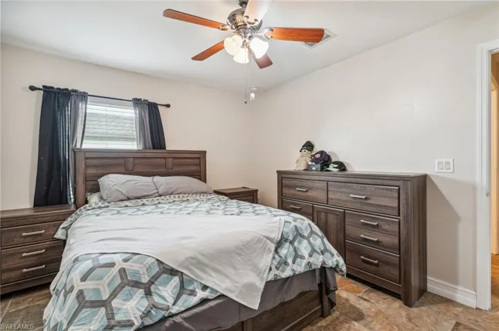 Tiled bedroom featuring ceiling fan