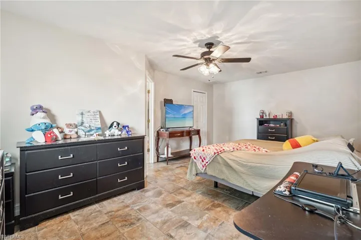 Tiled bedroom featuring ceiling fan and a closet