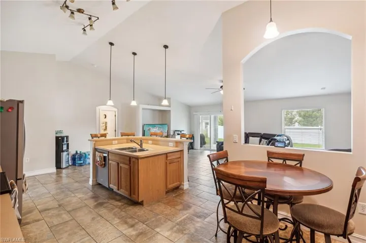 Kitchen with appliances with stainless steel finishes, light tile patterned flooring, a center island with sink, and rail lighting
