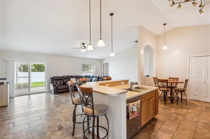 Kitchen featuring sink, a center island with sink, hanging light fixtures, and stainless steel dishwasher