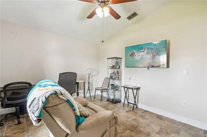 Living room featuring vaulted ceiling, tile patterned flooring, and ceiling fan