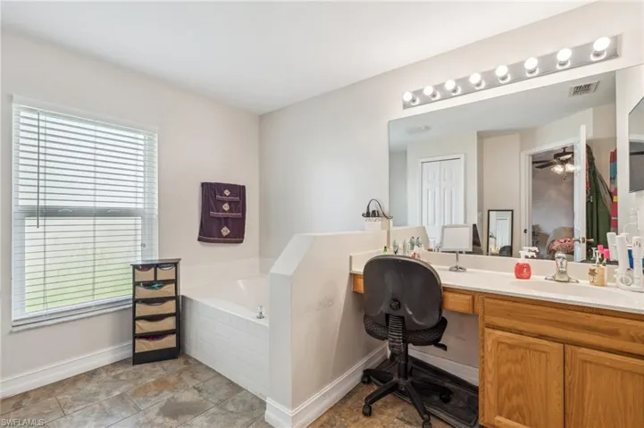 Bathroom with tile patterned floors, vanity, a bathtub, and ceiling fan