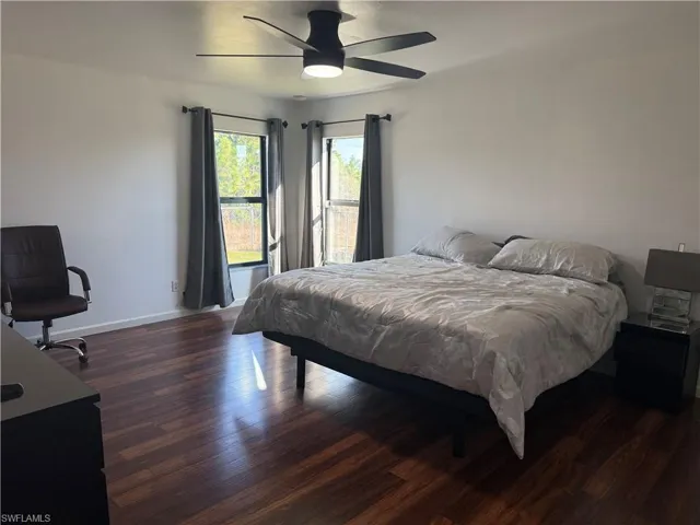 Master bedroom featuring dark laminate wood-type flooring and ceiling fan, two windows offering plenty of natural light.