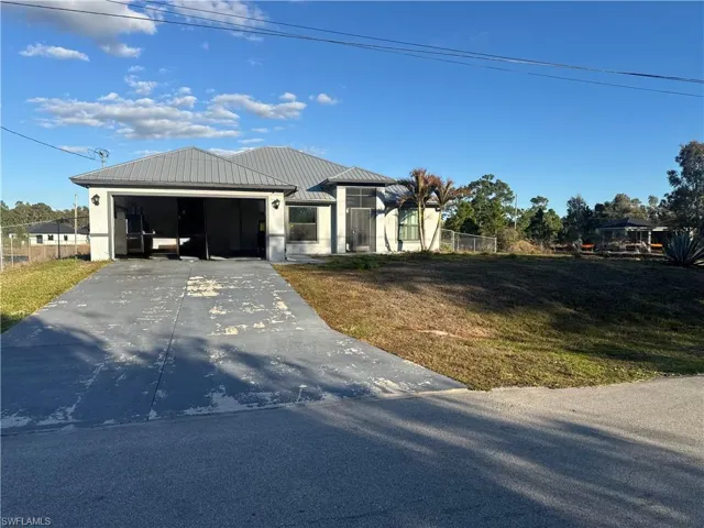 View of front facade with driveway, garage, and a metal roof