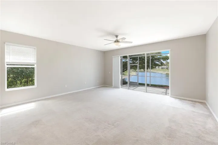 Spacious room featuring light-toned carpeting, neutral wall paint, and a ceiling fan with integrated lighting