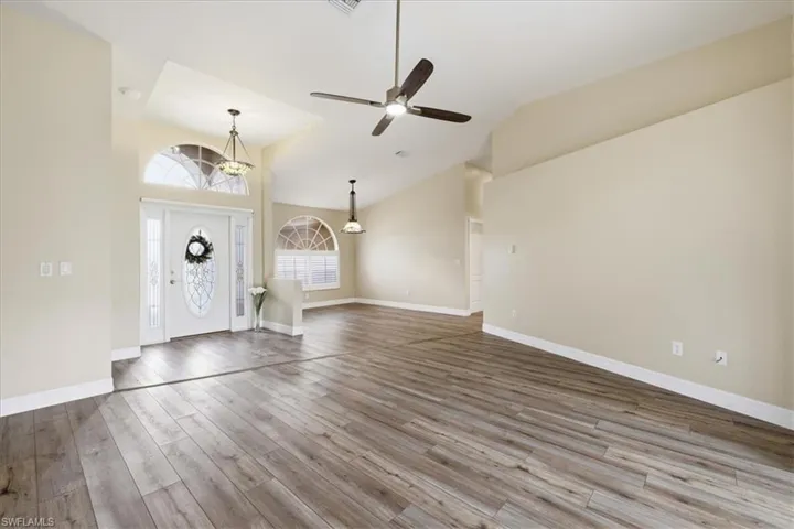 Spacious entry and living area featuring wood-finish flooring, vaulted ceilings, and a ceiling fan