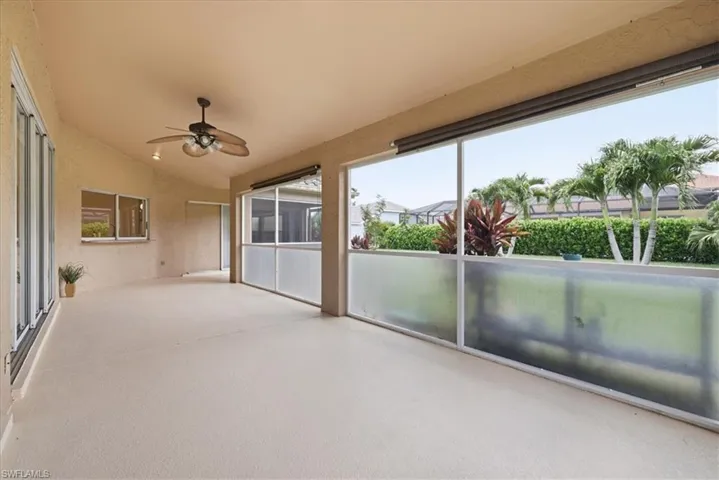 Expansive screened patio featuring a textured floor, a ceiling fan with integrated lighting, and multiple sliding glass doors