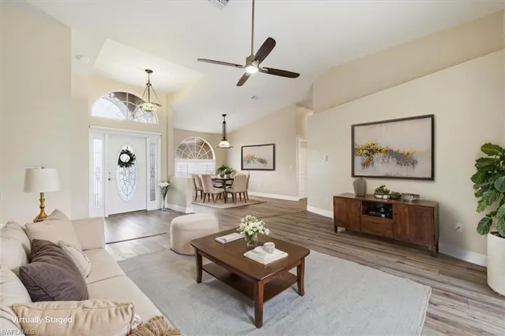 *VIRTUALLY STAGED* Vaulted ceilings above a bright entry with a decorative glass door and sidelights, complemented by wood-finish flooring