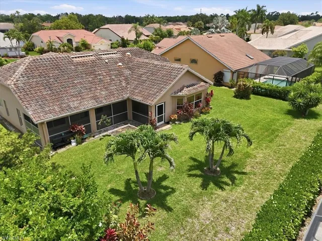 Expansive backyard featuring a manicured lawn, two mature palm trees, and established perimeter hedges