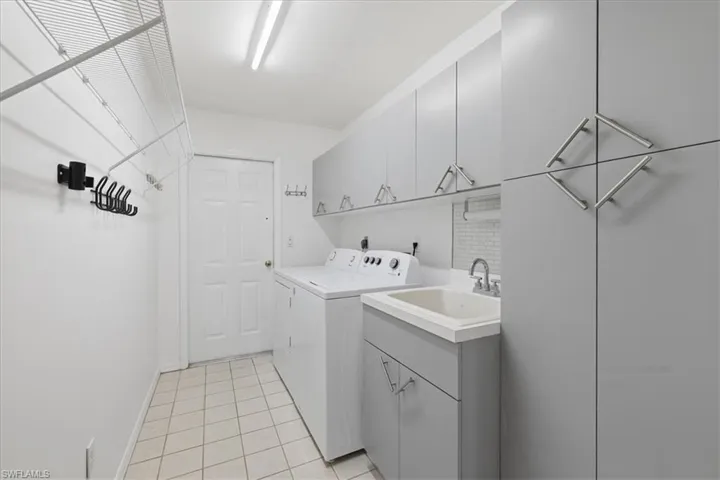 Laundry room with extensive gray cabinetry, utility sink, tile flooring, and integrated wire shelving