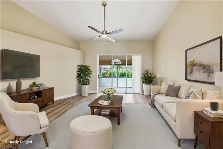 *VIRTUALLY STAGED* Vaulted ceilings enhance this living space featuring wood-finish flooring, a ceiling fan with integrated lighting, and direct access to an outdoor area via sliding glass doors