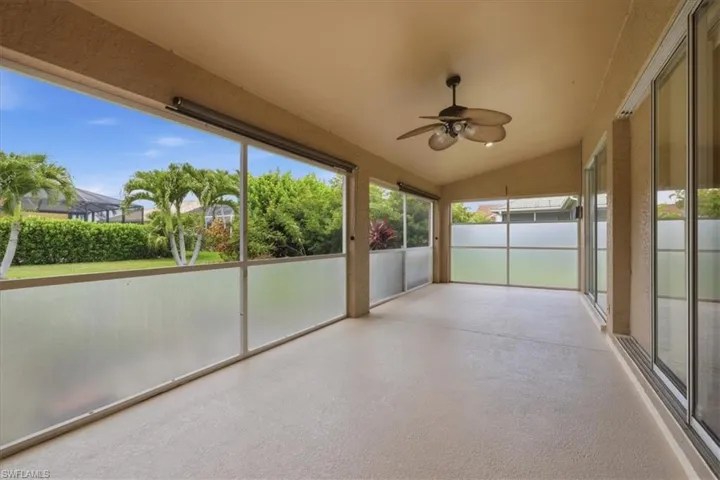Screened patio featuring a sloped ceiling, overhead fan with integrated lighting, and textured flooring