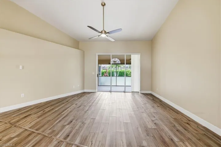 Expansive room featuring wood-finish flooring, vaulted ceilings, and a ceiling fan with integrated lighting