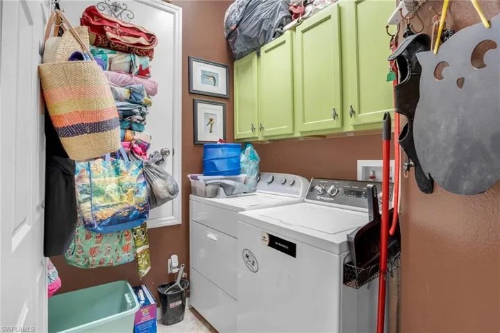 Washroom featuring cabinets and washer and clothes dryer