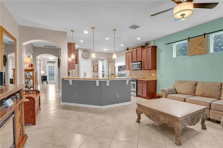 Kitchen featuring light tile patterned floors, backsplash, stainless steel appliances, and ceiling fan