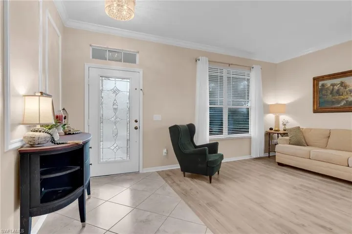Foyer entrance featuring ornamental molding, light wood-type flooring, plenty of natural light, and a chandelier