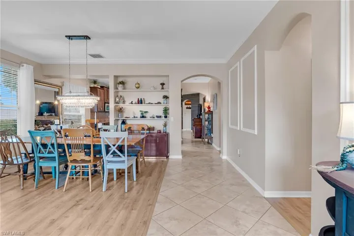 Dining space featuring built in features, crown molding, a notable chandelier, and light tile patterned flooring