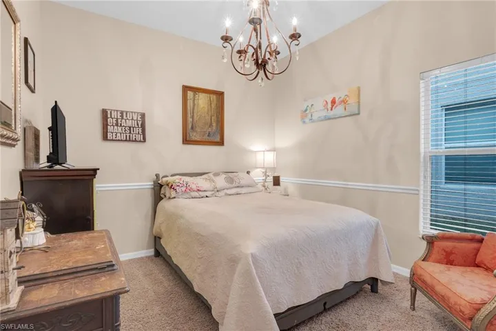 Bedroom featuring lofted ceiling, carpet flooring, and a chandelier