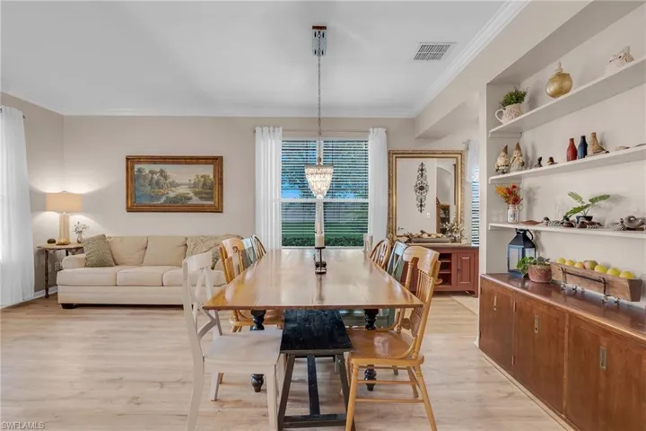 Dining room with crown molding, light hardwood / wood-style flooring, and a notable chandelier