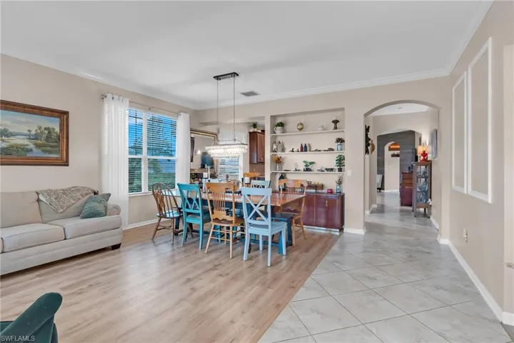 Dining room with built in features, crown molding, an inviting chandelier, and light wood-type flooring