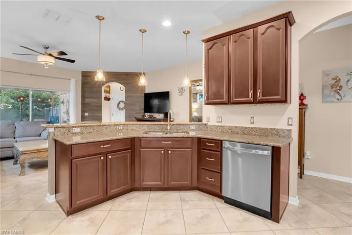 Kitchen featuring dishwasher, light stone counters, light tile patterned floors, and ceiling fan
