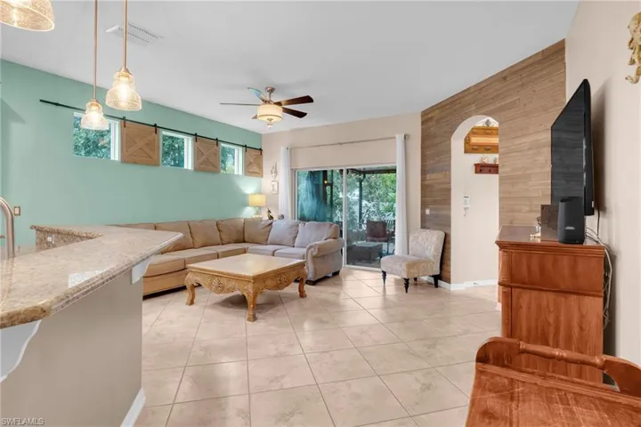 Tiled living room with wood walls, ceiling fan, and tile walls
