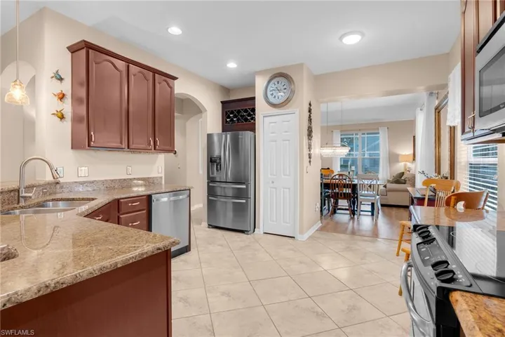 Kitchen with pendant lighting, light stone counters, sink, appliances with stainless steel finishes, and light hardwood / wood-style floors