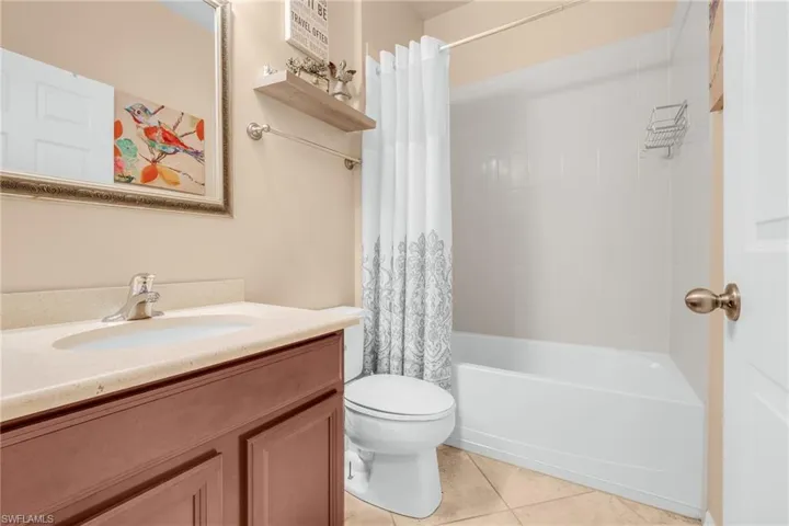 Full bathroom featuring tile patterned flooring, vanity, toilet, and shower / tub combo with curtain