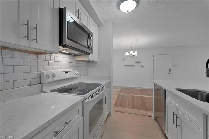 Kitchen features quartz counter tops and white shaker cabinets.