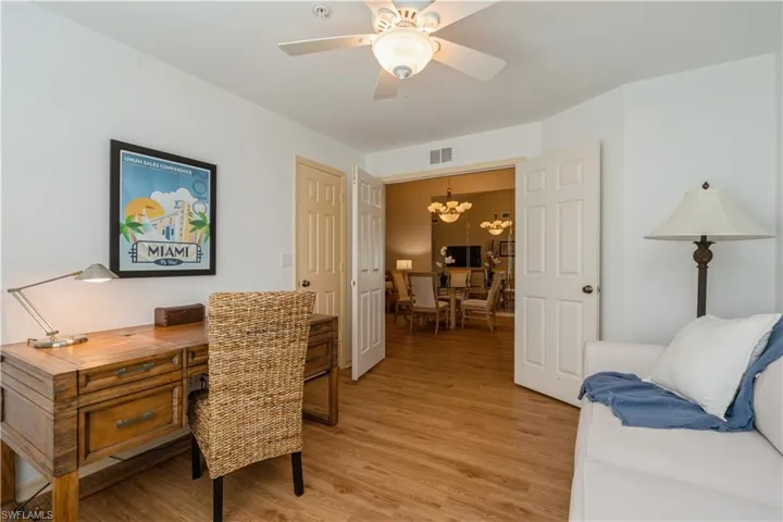 Home office with light hardwood / wood-style flooring and ceiling fan with notable chandelier