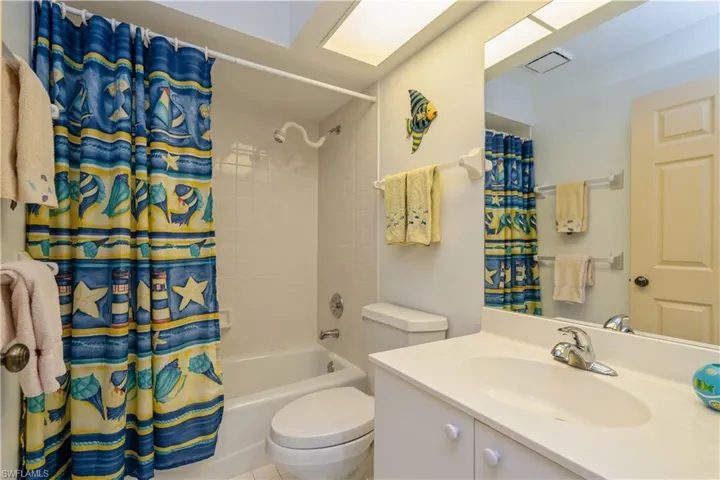 Full bathroom featuring toilet, shower / tub combo with curtain, vanity, and tile patterned flooring