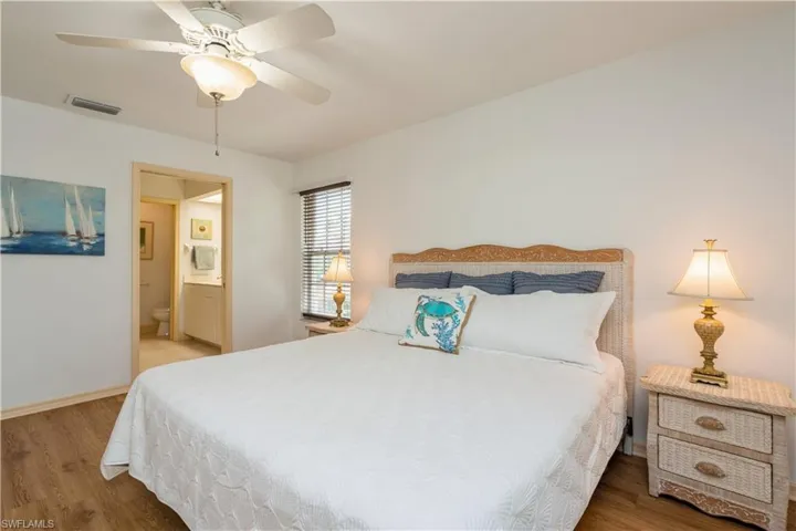 Bedroom featuring hardwood / wood-style flooring, ensuite bath, and ceiling fan