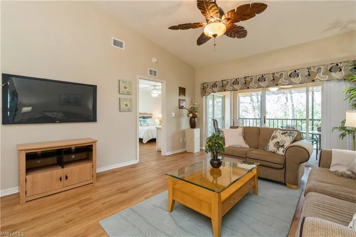Living room with ceiling fan, high vaulted ceiling, and light wood-type flooring