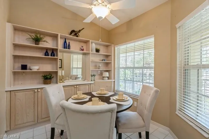 Tiled dining space with lofted ceiling, a healthy amount of sunlight, and ceiling fan