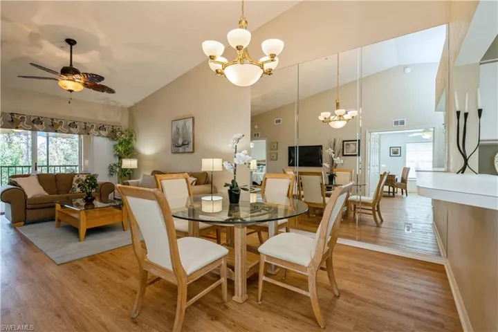 Dining space with light hardwood / wood-style flooring, high vaulted ceiling, and ceiling fan with notable chandelier