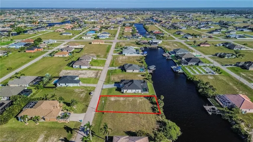 Aerial perspective of suburban area with property boundaries highlighted and a nearby body of water