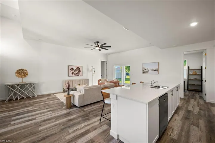 Kitchen featuring an island with sink, white cabinets, ceiling fan, and hardwood / wood-style floors