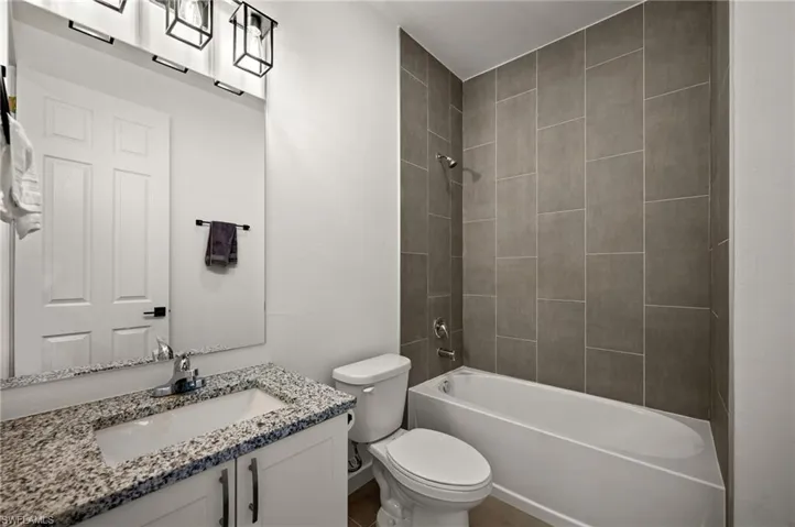 Full bathroom with tiled shower / bath, toilet, and vanity