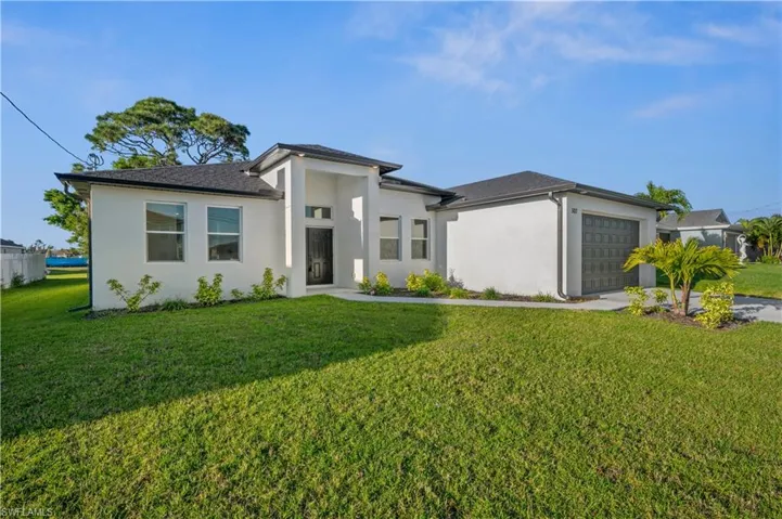 View of front facade featuring a garage and a front yard