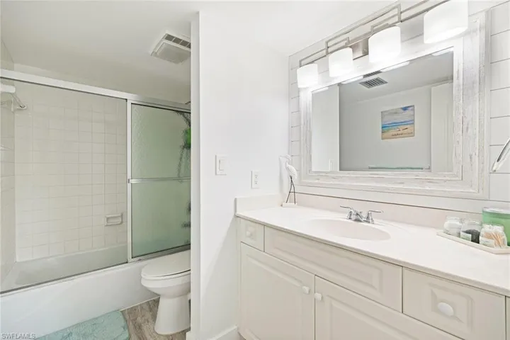 Full bathroom with vanity, enclosed tub / shower combo, and light wood finished floors