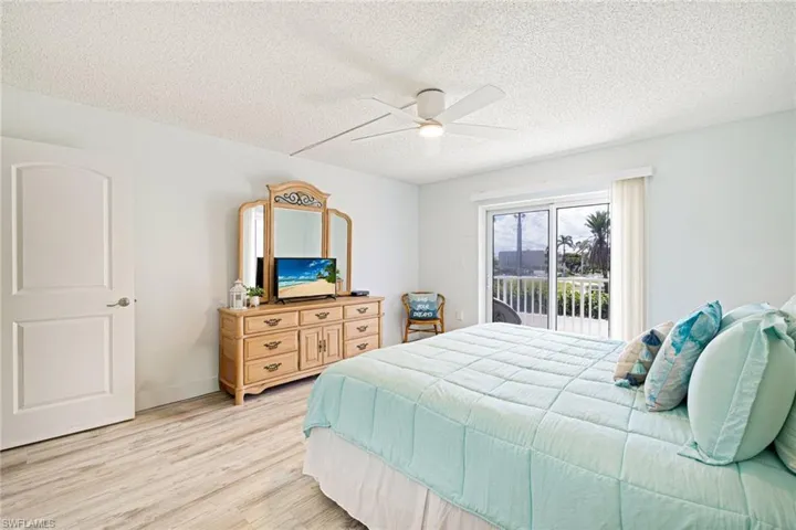 Bedroom featuring a textured ceiling, light wood-type flooring, access to exterior, and a ceiling fan