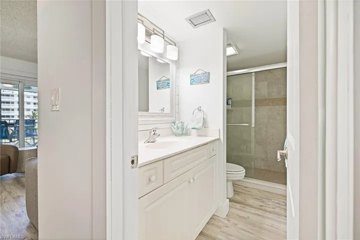 Full bathroom featuring light wood-style flooring, a shower stall, vanity, and a textured ceiling