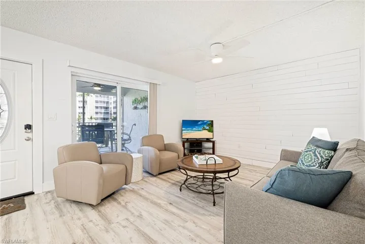 Living area with a textured ceiling, wood finished floors, wooden walls, and ceiling fan