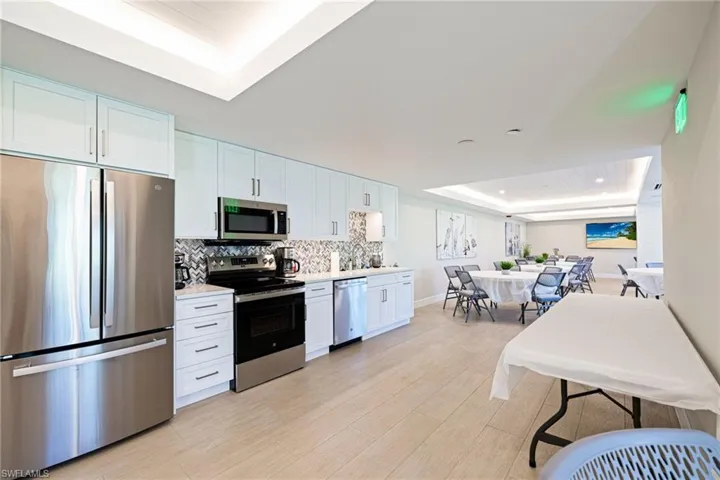 Kitchen featuring a raised ceiling, appliances with stainless steel finishes, white cabinetry, and light wood-type flooring